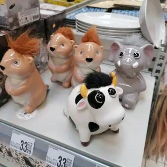 Ceramic animal money boxes on a shop shelf beside price labels