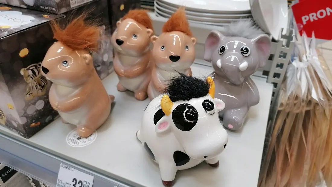 Ceramic animal money boxes on a shop shelf beside price labels