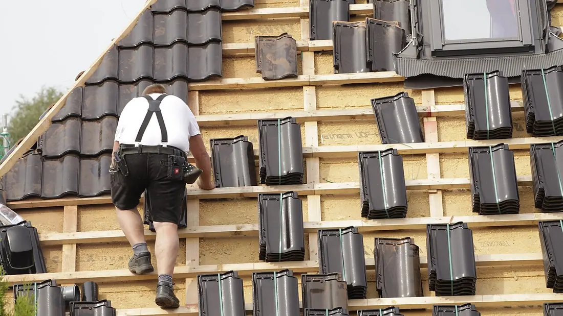 A roofer laying tiles on a pitched roof