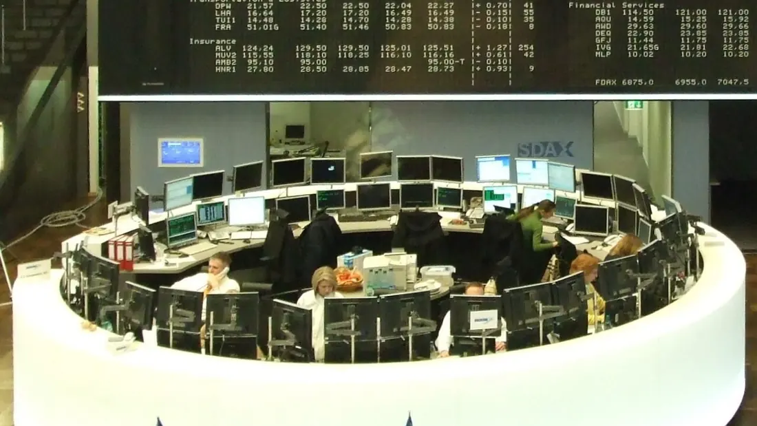 A broker on the telephone in front of a stock index board