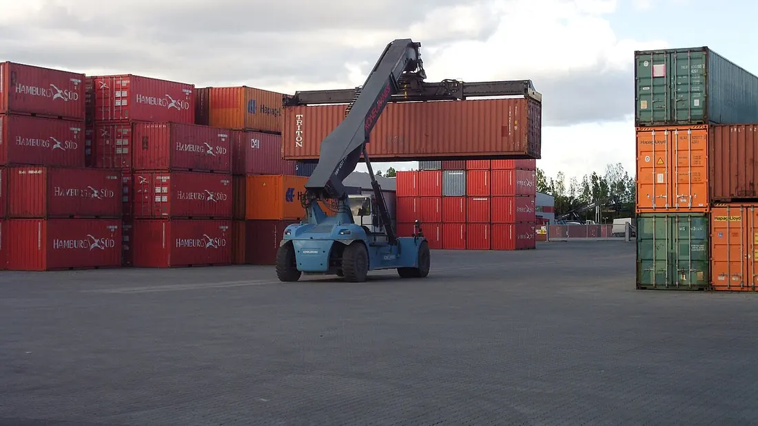 A gantry crane lifting shipping containers at a quay