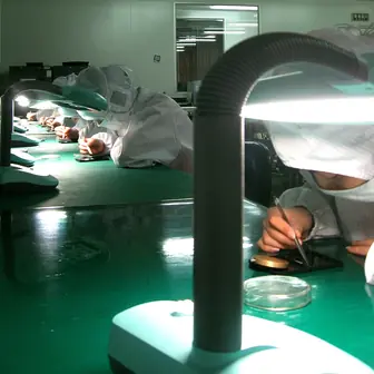 Workers at benches along a factory assembly line