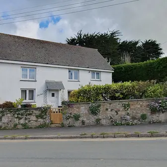 A detached stone house behind a low wall