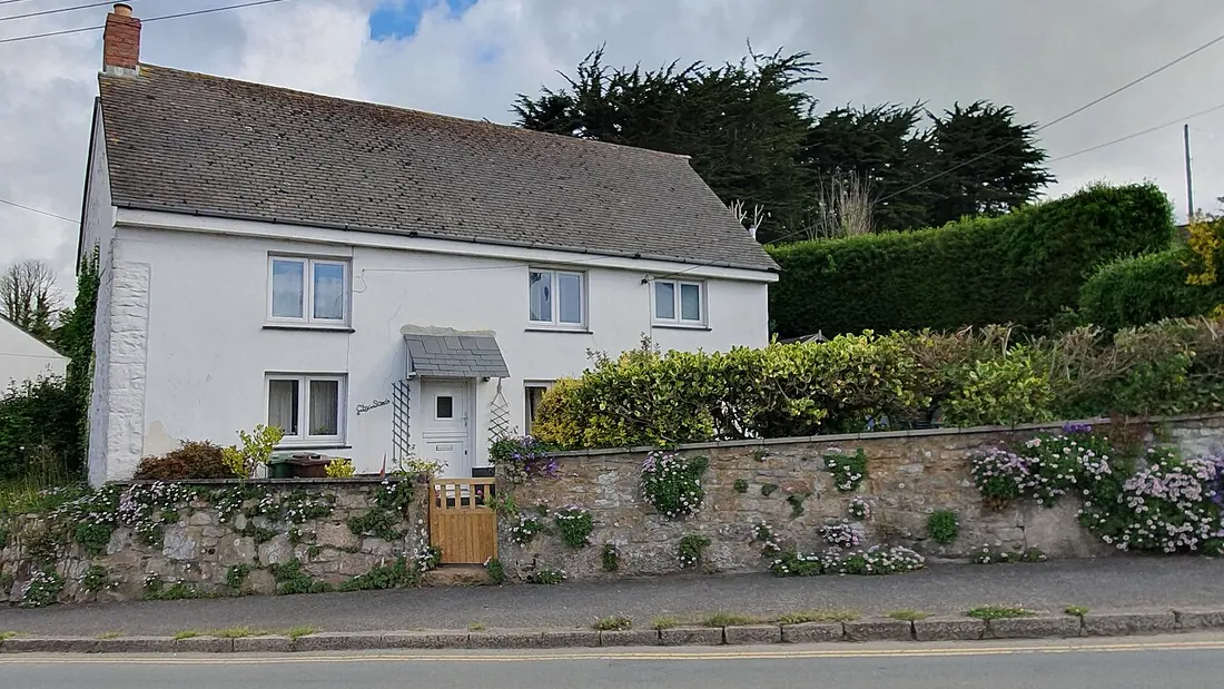 A detached stone house behind a low wall