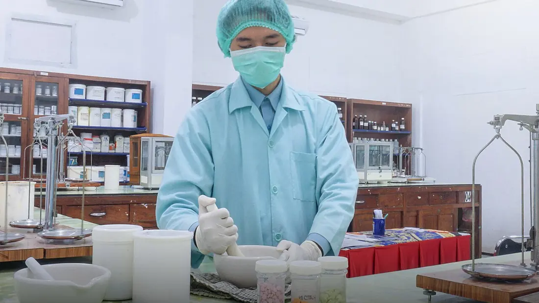 A pharmacy worker handing out medicines at a dispensary counter