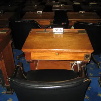 A wooden desk in a legislative chamber
