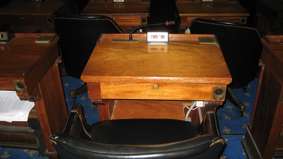 A wooden desk in a legislative chamber